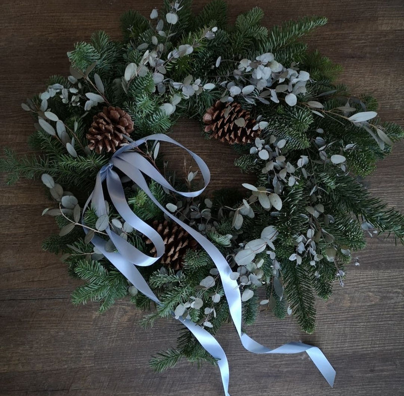 Winter Wreath with pine cedar and eucalyptus. Blue ribbon and pine cones