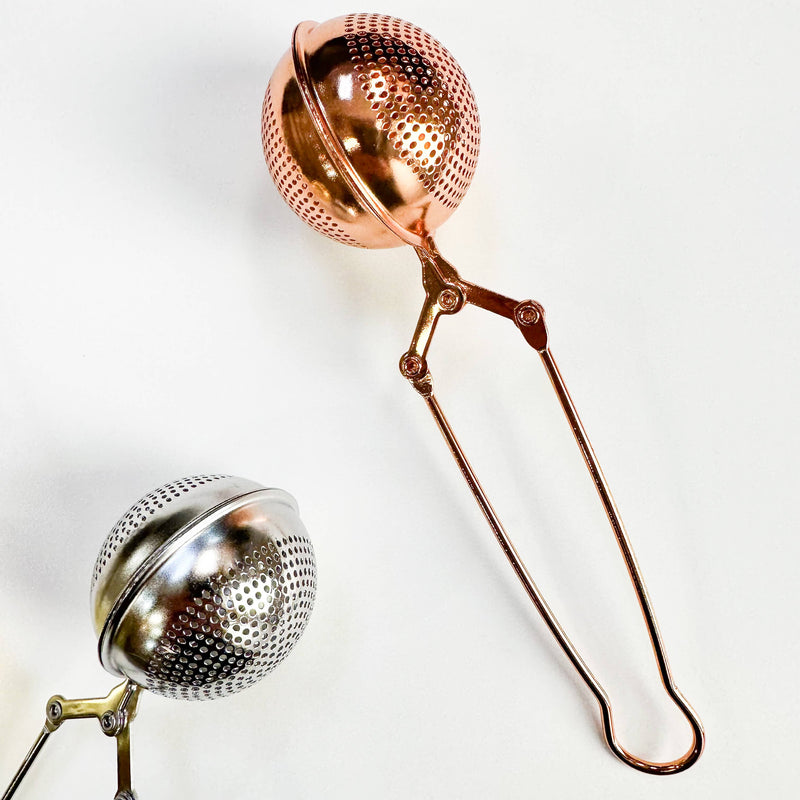 Copper and silver tea infusers on a white background