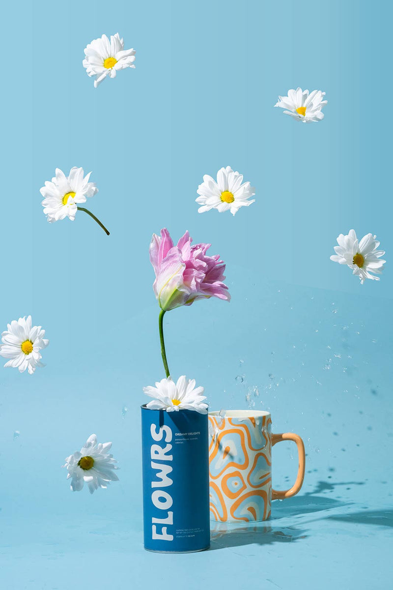 Flower arrangement in a mug labeled 'FLOWERS' against a blue background with scattered daisies.