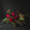 Floral arrangement with red flowers and greenery on a black background
