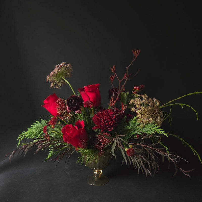 Floral arrangement with red flowers and greenery on a black background