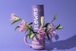 Purple mug with floral arrangement and 'FLOWRS' container on a purple background