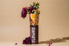 Flower arrangement in a canister labeled 'FLOWRS' on a beige background