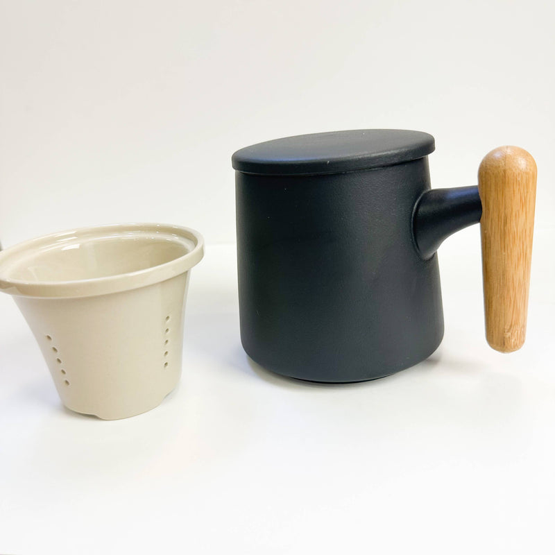 Black mug with wooden handle and beige filter on a white background