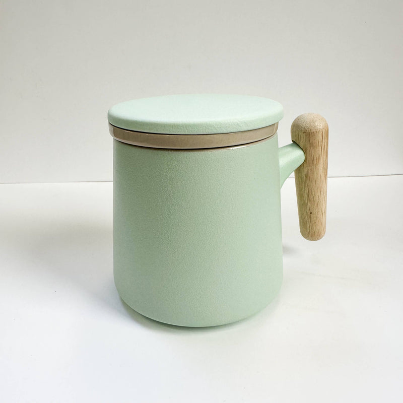 Mint green mug with a wooden handle and lid on a white background