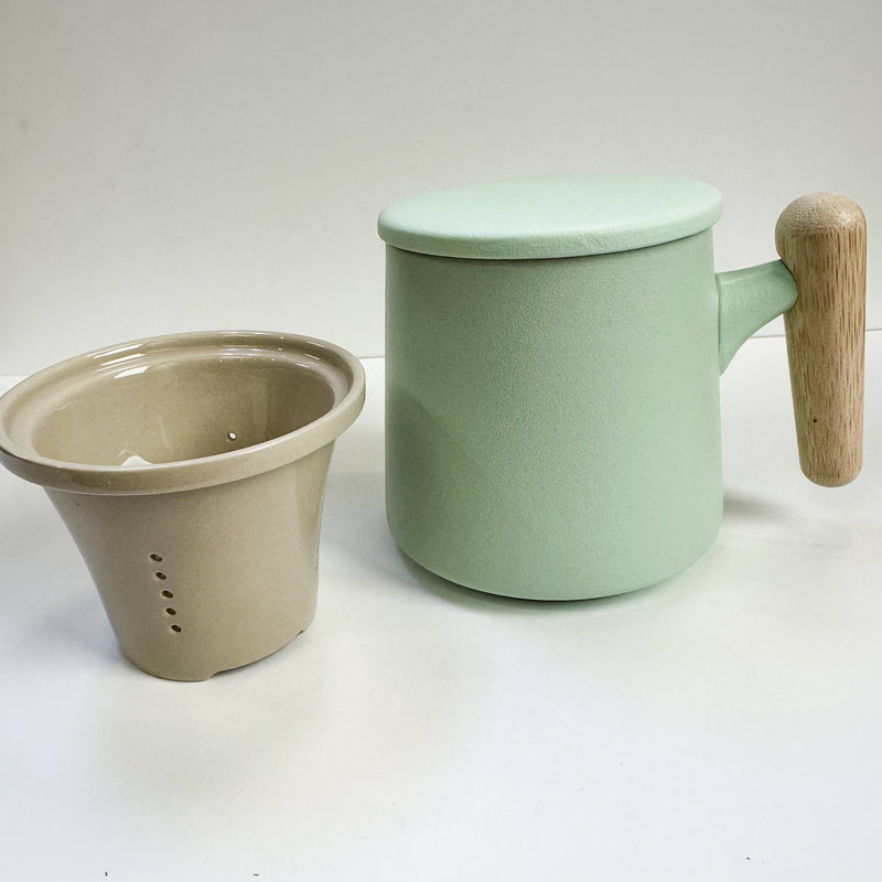 Green ceramic mug with wooden handle and beige ceramic filter on a white background