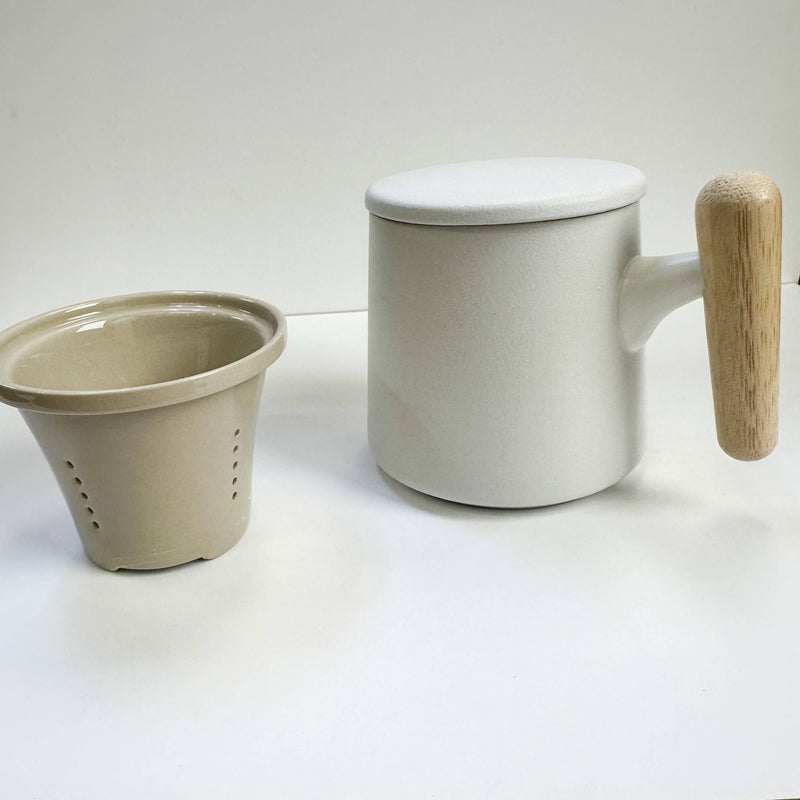 White ceramic mug with wooden handle and beige ceramic filter on a white background
