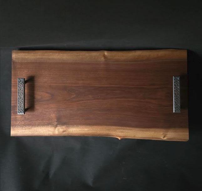 Wooden cutting board with decorative handles on a black background