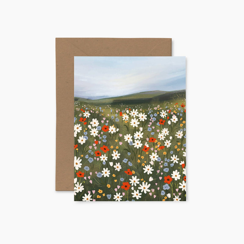 A greeting card featuring a colorful illustration of a summer field with various flowers, accompanied by a brown envelope.